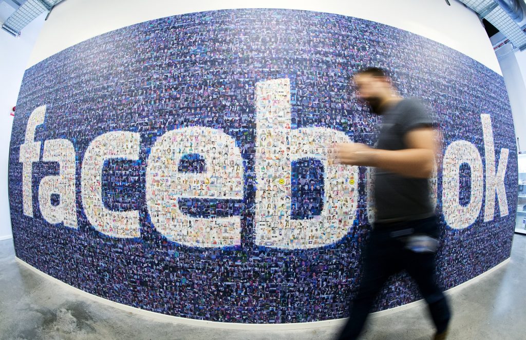 This picture taken with a fisheye lens shows a man walks past a big logo created from pictures of Facebook users worldwide in the company's Data Center, its first outside the US on November 7, 2013 in Lulea, in Swedish Lapland. The company began construction on the facility in October 2011 and went live on June 12, 2013 and are 100% run on hydro power. AFP PHOTO/JONATHAN NACKSTRAND        (Photo credit should read JONATHAN NACKSTRAND/AFP/Getty Images)